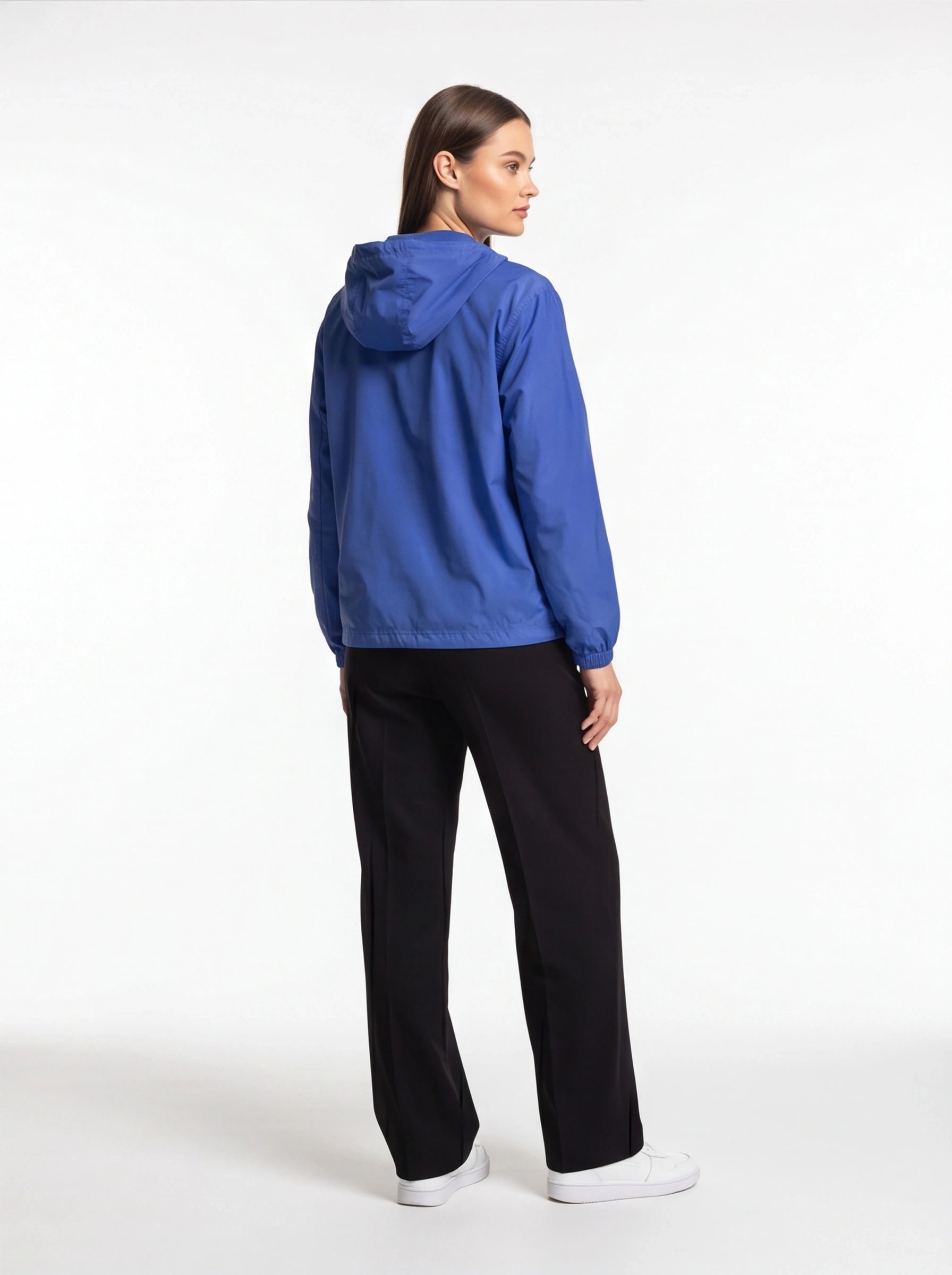 Person wearing a blue jacket and black pants on a white background